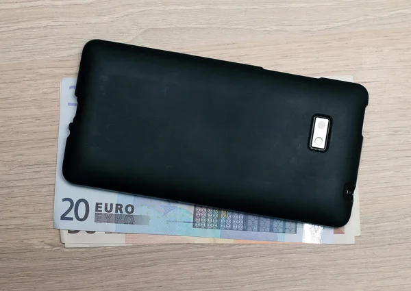 Dinheiro em euros e um telemóvel em cima da mesa — Fotografia de Stock