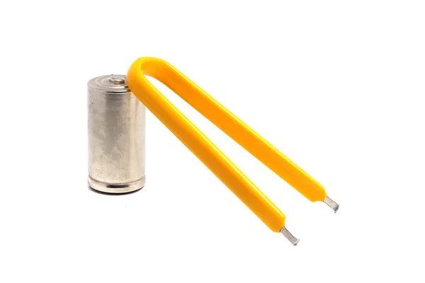 Yellow tweezers and a large battery on a white background — Stock Photo, Image