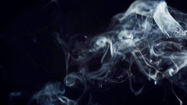 unhealthy lifestyle . cigarette smoke clouds draws artistic abstract patterns. dark background