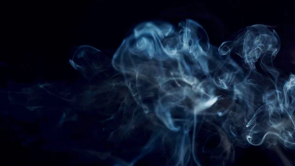 unhealthy lifestyle . cigarette smoke clouds draws artistic abstract patterns. dark background