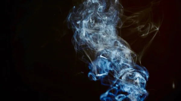 unhealthy lifestyle . cigarette smoke clouds draws artistic abstract patterns. dark background