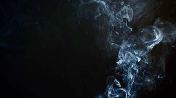 Unhealthy lifestyle . cigarette smoke clouds draws artistic abstract patterns. dark background