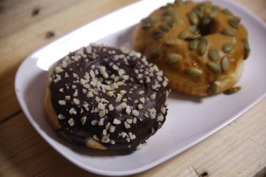 Beyaz bir tabakta iki farklı aromalı çörek. Düşük ışık.