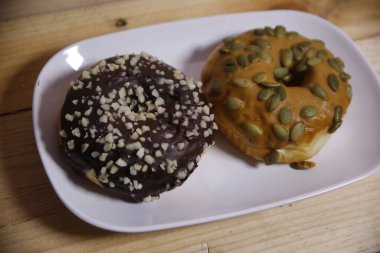 Beyaz bir tabakta iki farklı aromalı çörek. Düşük ışık.