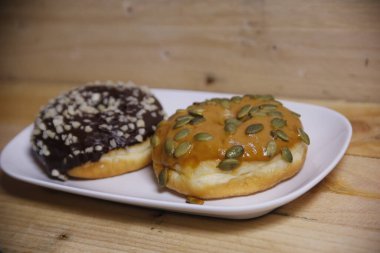 Beyaz bir tabakta iki farklı aromalı çörek. Düşük ışık.
