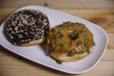 Beyaz bir tabakta iki farklı aromalı çörek. Düşük ışık.