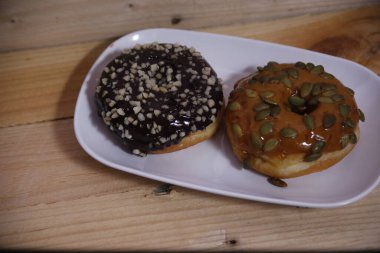 Beyaz bir tabakta iki farklı aromalı çörek. Düşük ışık.