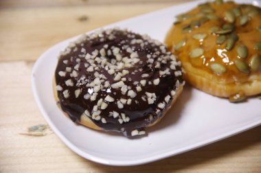 Beyaz bir tabakta iki farklı aromalı çörek. Düşük ışık.