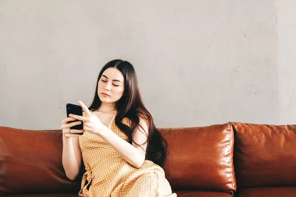 Mujer Joven Caucásica Usando Teléfono Inteligente Mientras Descansa Elegante Sofá — Foto de Stock