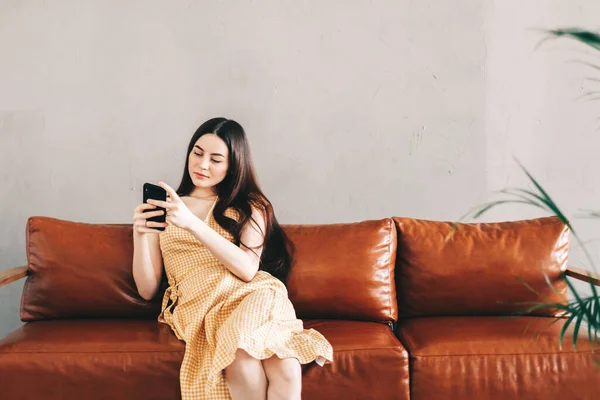 Mujer Joven Caucásica Usando Teléfono Inteligente Mientras Descansa Elegante Sofá — Foto de Stock