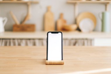 Mutfaktaki ahşap masada dikey beyaz ekranlı akıllı telefon. Yüksek kalite fotoğraf