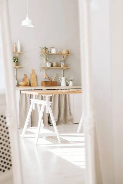 Mirror reflection of bright kitchen in the Provence style with houseplants, wooden dishes and kitchen accessories on the table and shelves.