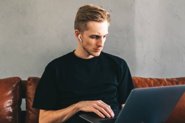 Kulaklıklarda odaklanmış beyaz adam mobil geliştirici, programcı merkez ofisteki bir dizüstü bilgisayara program kodu yazar. Yüksek kalite fotoğraf