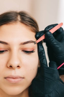 Kaş şekillendirme prosedürü, makyaj ustası cımbız ve kaşları şekillendirmek için fırça kullanır. Yüksek kalite fotoğraf