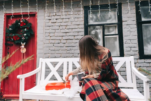 年轻的高加索女人坐在后院的长椅上 打开了圣诞礼物 高质量的照片 — 图库照片