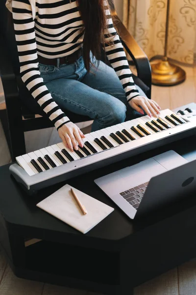 年轻女人在家里远程学习用笔记本电脑弹钢琴. — 图库照片