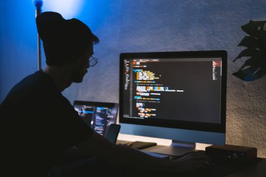 Genç adam mobil geliştirici bir bilgisayara program kodu yazar, programcı da merkez ofiste çalışır. Yüksek kalite fotoğraf