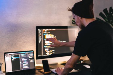 Genç adam mobil geliştirici bir bilgisayara program kodu yazar, programcı da merkez ofiste çalışır. Yüksek kalite fotoğraf