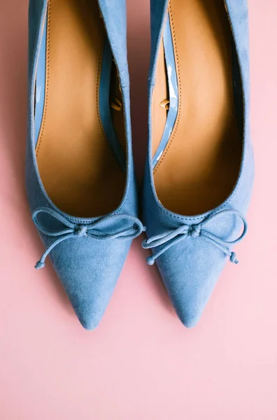 Blue womens shoes with heels on pink background.