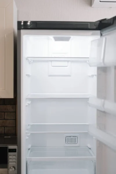 Empty open white refrigerator in the kitchen. High quality photo