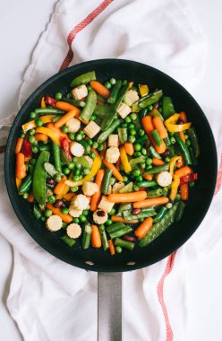 Taze sebzeler beyaz masada siyah bir tavada karıştırılır. Sağlıklı yiyecekler. Yüksek kalite fotoğraf