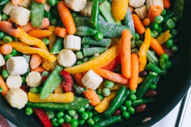 Taze sebzeler beyaz masada siyah bir tavada karıştırılır. Sağlıklı yiyecekler. Yüksek kalite fotoğraf