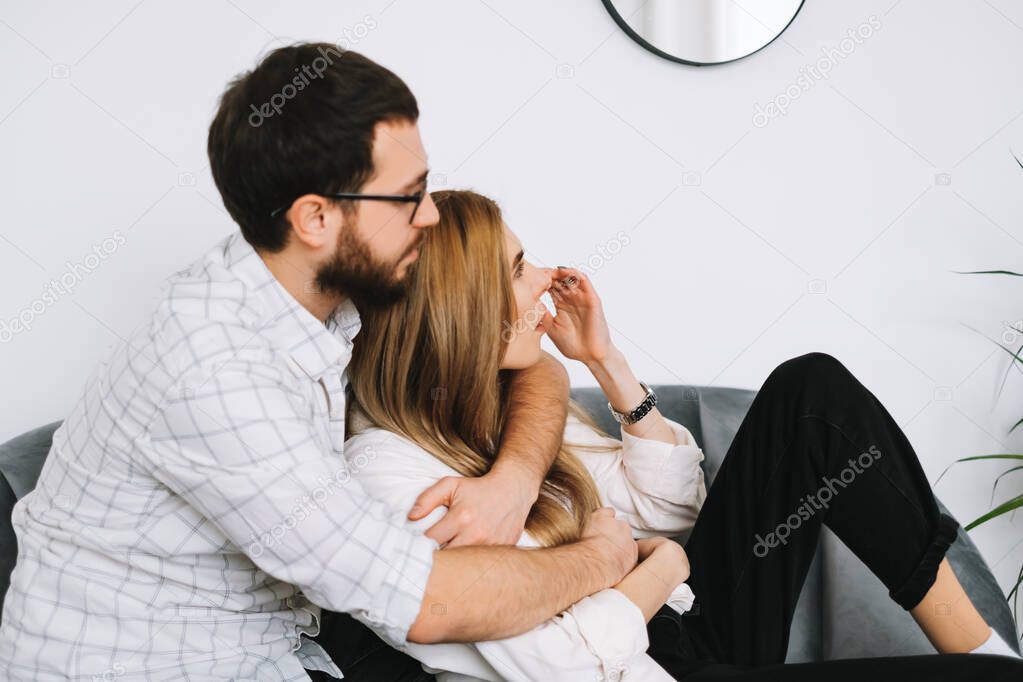 Cheerful couple sitting on the sofa at home near white wall. High quality photo