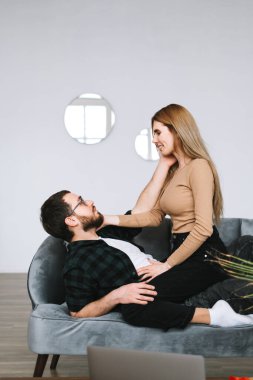 Genç mutlu çift evdeki kanepede dinleniyor, nazikçe birbirlerine dokunuyorlar. Yüksek kalite fotoğraf