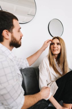 Genç mutlu çift evdeki kanepede dinleniyor, nazikçe birbirlerine dokunuyorlar. Yüksek kalite fotoğraf