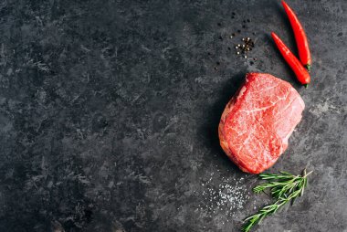 Siyah arka planda çiğ biftek, biberiye, biber ve baharat, kopyalama alanı..