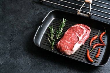 Biberiyeli ve biberiyeli, siyah ızgara tavada çiğ biftekli biftek..