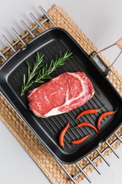 Biberiyeli ve biberiyeli, siyah ızgara tavada çiğ biftekli biftek..