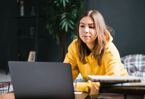 Young woman college student studying with laptop, distantly preparing for test exam, writing essay doing homework at home, distantly education concept