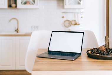 Beyaz beyaz ekranlı dizüstü bilgisayar, parlak modern mutfak masasının üstünde..