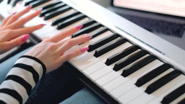 Mladá žena se naučí hrát klávesy pomocí notebooku, zblízka. — Stock video