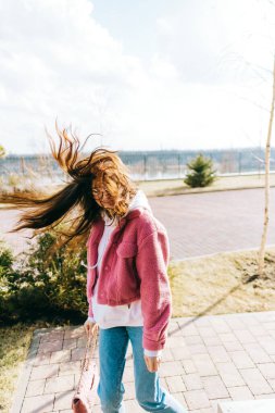 Parkta yürüyen ve güneşli bir günde bahar havasının tadını çıkaran neşeli beyaz kadın portresi..