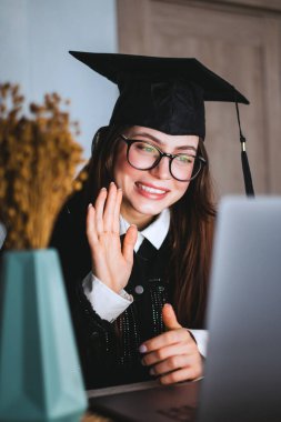 Mutlu beyaz kadın üniversite mezuniyetini arkadaşlarıyla ya da aileleriyle video görüşmesinde kutluyor..
