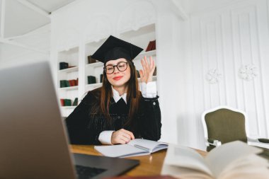 Mutlu beyaz kadın üniversite mezuniyetini arkadaşlarıyla ya da aileleriyle video görüşmesinde kutluyor. Çevrimiçi mezuniyet töreni kavramı