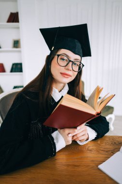 Kütüphanede kitabı olan kendine güvenen beyaz kadın öğrencinin portresi üniversite mezuniyetini kutluyor.