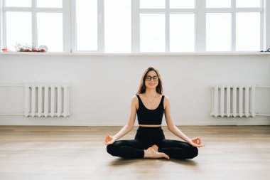 Güzel esmer kadın meditasyon yapıyor, evde yoga yapıyor. Formda ve sağlıklı kalmak.