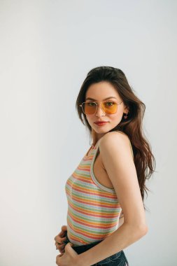 Stüdyoda uzun esmer saçlı, güneş gözlüklü çekici bir kadının portresi..