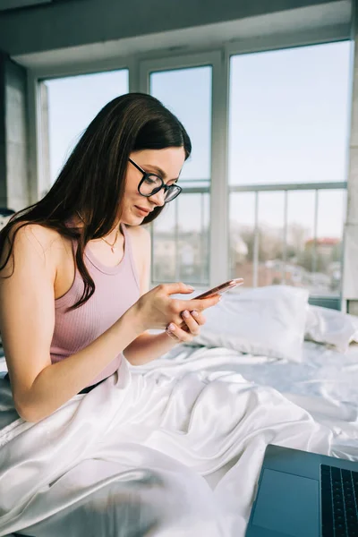 Young Caucasian Woman Resting Bed Home Using Laptop Computer Smartphone — Stock Fotó