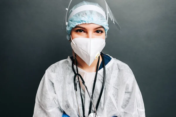 Young woman nurse hospital worker in medical protective mask, gloves and protective wear isolated on gray background.