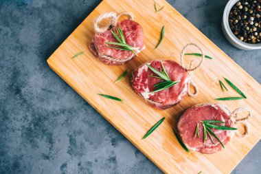 Biberiye ve baharatla ahşap bir tahtada çiğ biftek mignon bifteği..