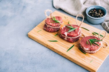 Biberiye ve baharatla ahşap bir tahtada çiğ biftek mignon bifteği..