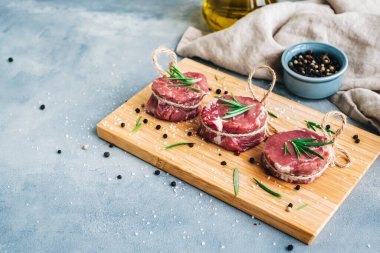 Biberiye ve baharatla ahşap bir tahtada çiğ biftek mignon bifteği..