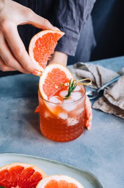 Kadın barmen, buzlu limonata ve biberiyeli taze greyfurttan meyve suyu sıkıyor..