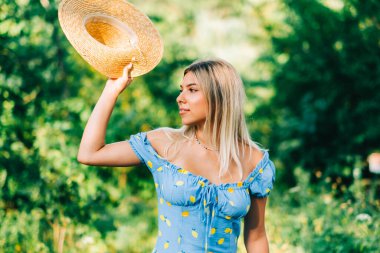 Yazın güneşli bir günde açık havada hasır şapkalı çekici genç bir kadının portresi..