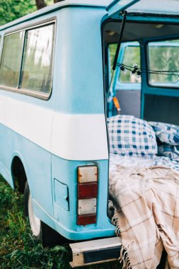 Doğada mavi-beyaz retro minibüs, rahat dekorasyonlar, battaniye ve yastık, doğa konseptinde tatiller