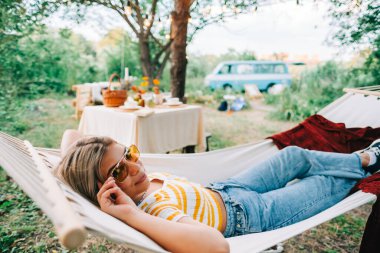 Arka bahçedeki hamakta dinlenen genç bir kadın. Keyifli yaz